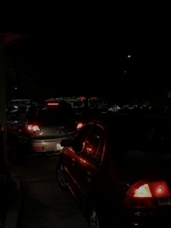 Tail lights glowing warmly as cars line up under softly lit trees in the evening