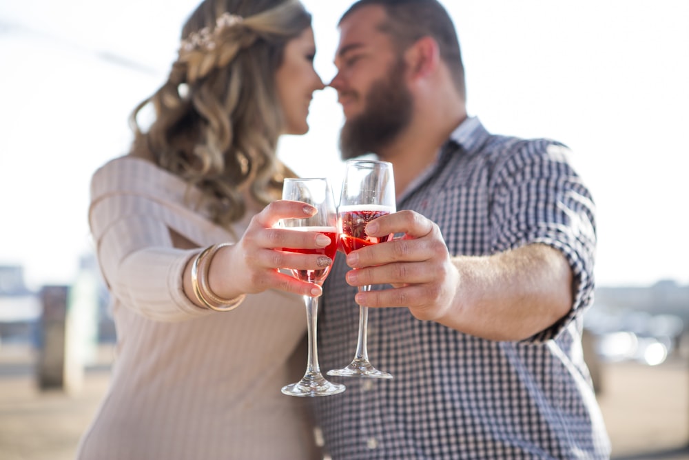 man in gray and white checkered dress shirt holding clear wine glass