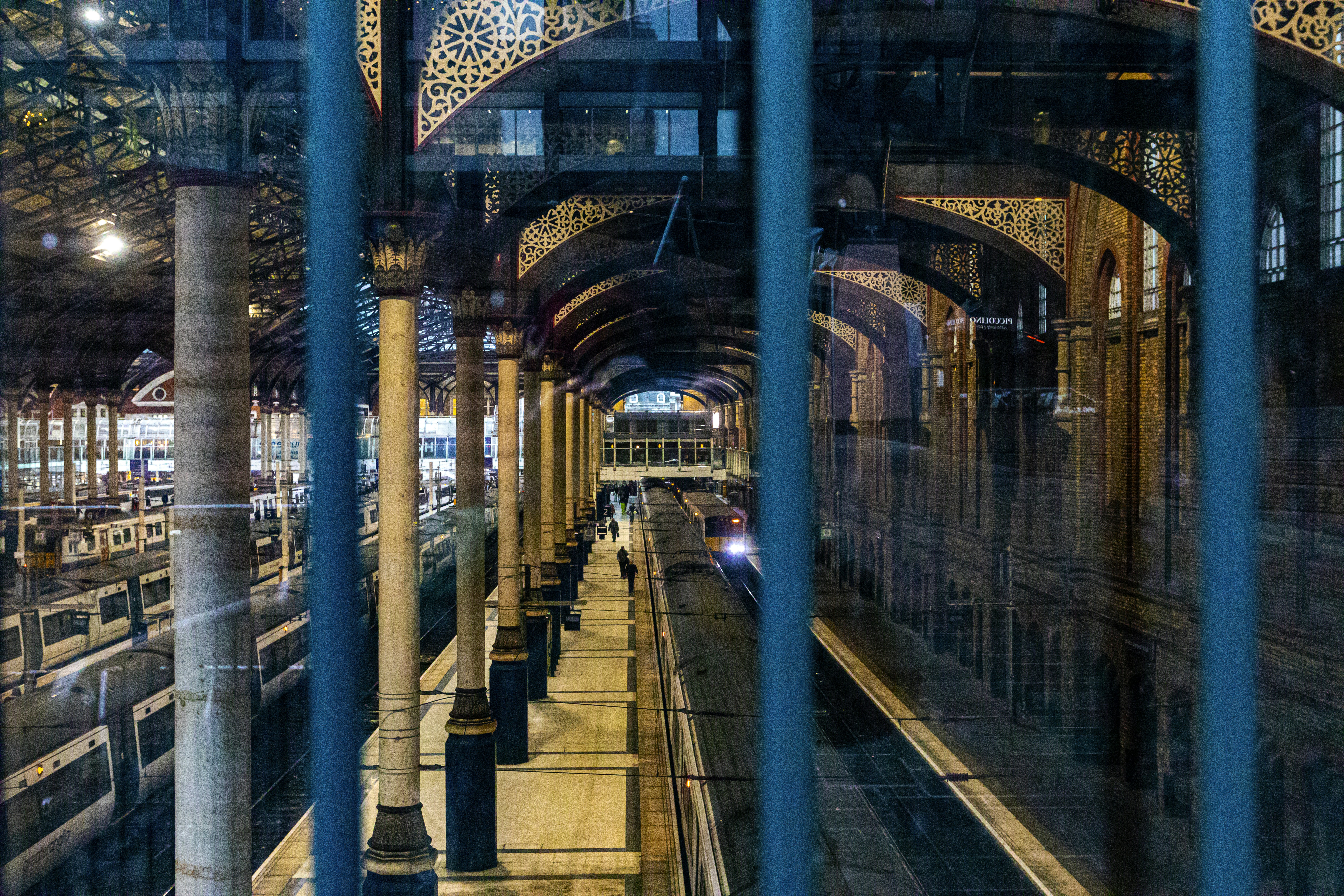 London, UK - Liverpool Street Train Station. Victorian design with modern rail now, from a window outside looking in through the bars.
