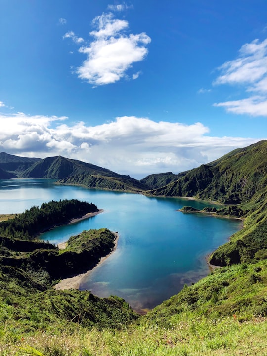 lake in the middle of mountains under blue sky in Lagoa do Fogo Portugal
