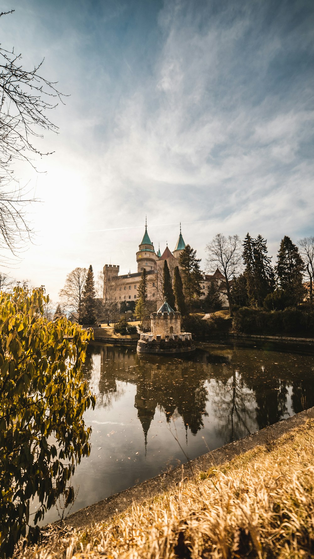 gray and black castle near body of water under cloudy sky during daytime