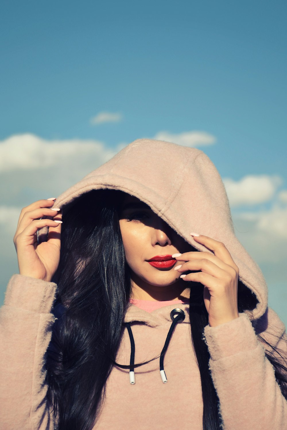 woman in gray hoodie covering her face with her hand