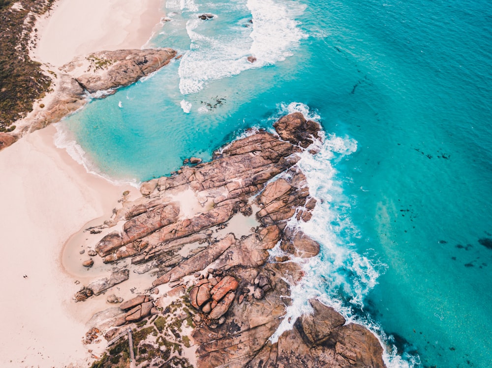 formação rochosa marrom na água azul do mar durante o dia