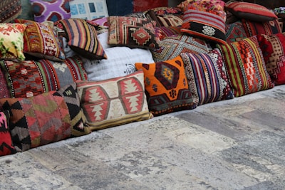 A colorful display of embroidered cushions arranged on a rustic wooden bench.