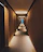 A softly lit hotel corridor with warm golden hues and elegant shadows, inviting guests inside.
