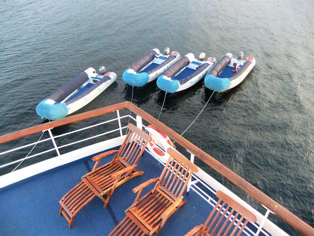 brown wooden chairs on blue and white boat on body of water during daytime