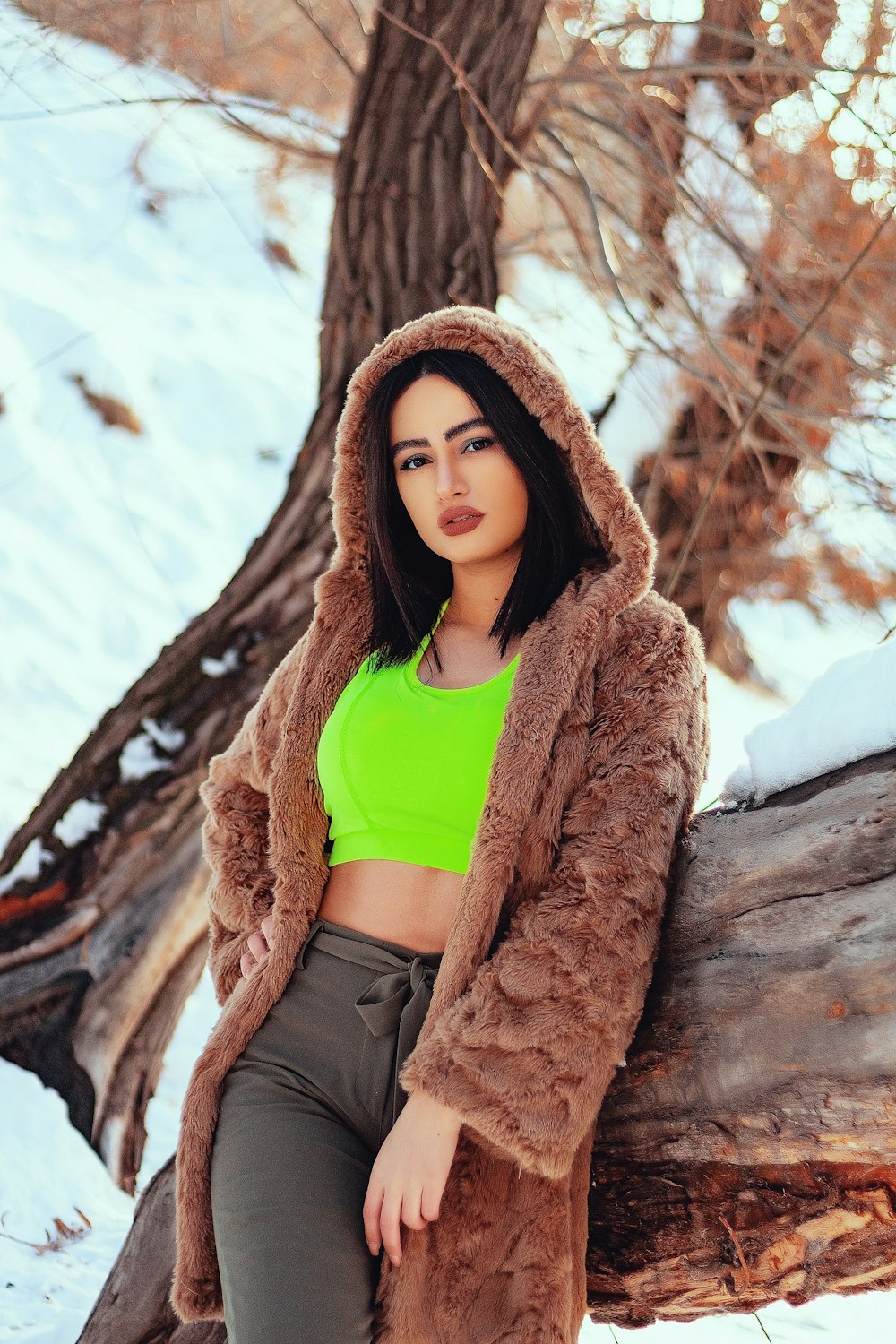 woman in brown fur coat and blue shirt sitting on brown rock during daytime