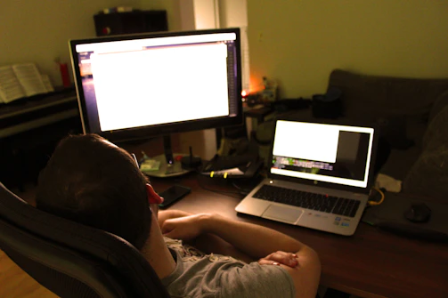 A friendly cybersecurity researcher at a desk with multiple screens showing data and network activity.