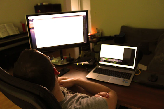 A focused analyst reviewing detailed soccer player stats on multiple screens in a cozy home office.