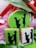 Three cookies displaying silhouettes of a couple, where one figure is kneeling and proposing to the other. The cookies are decorated with green and white icing, with floral and ribbon adornments in the background.