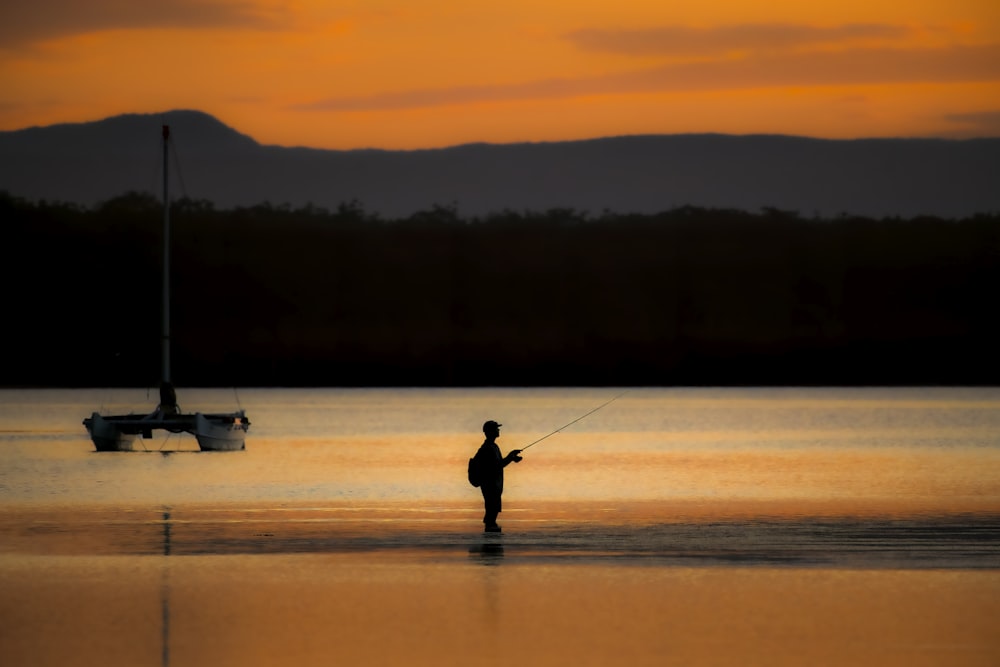 a man standing in the water with a fishing rod