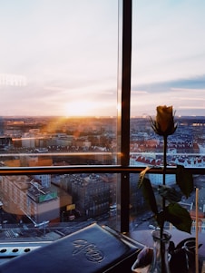 man in blue jacket sitting on chair near glass window during sunset