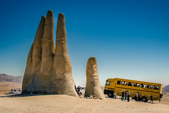 people sitting on brown sand near yellow bus during daytime in Antofagasta Chile