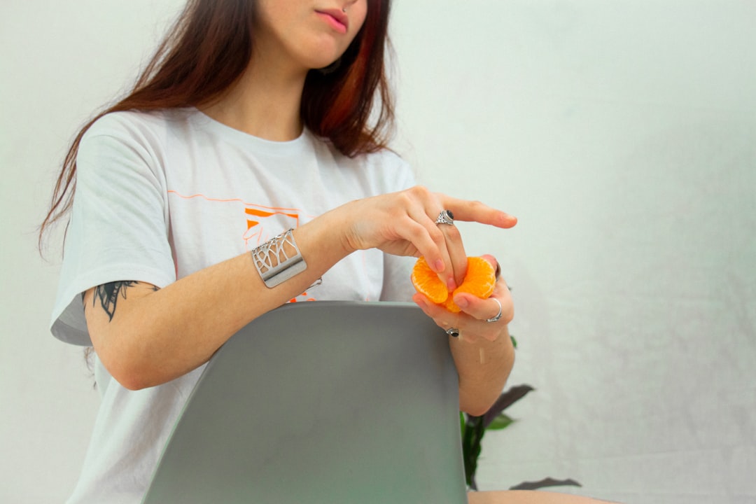 woman in white crew neck t-shirt holding orange fruit
