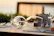 Close-up of a wine bottle and glasses set on a rustic wooden table along a hiking path.