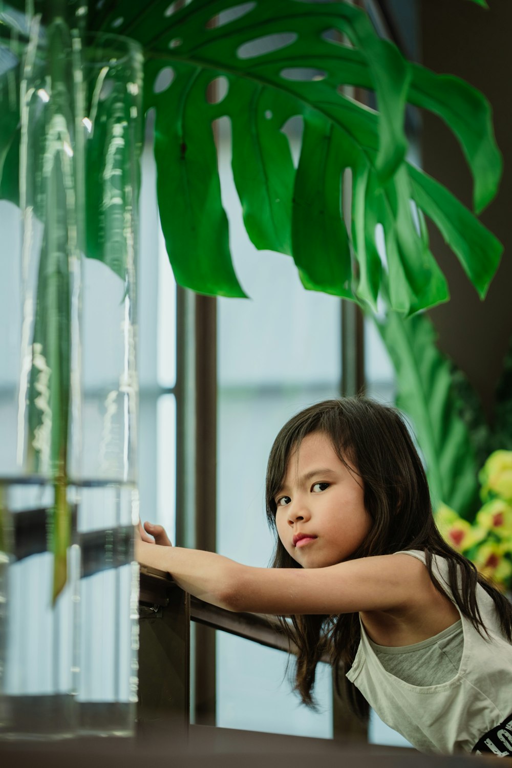 girl in black tank top standing beside green plant during daytime