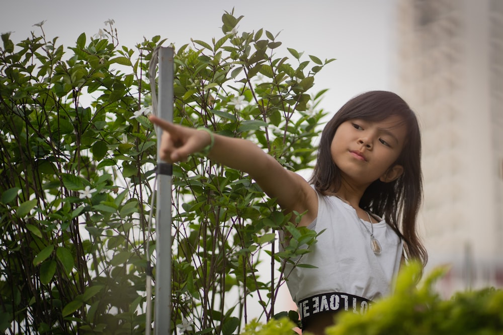 woman in white crew neck t-shirt standing beside green plants during daytime