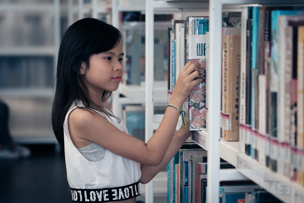 woman in white tank top holding book