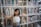 Happy young girl holding books in a classroom with colorful educational posters.