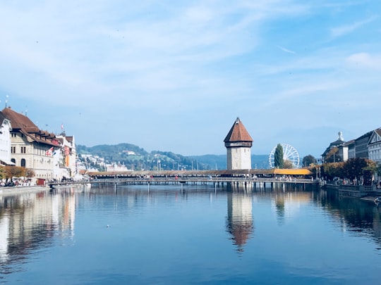 white and brown concrete building near body of water during daytime in Kapellbrücke Switzerland