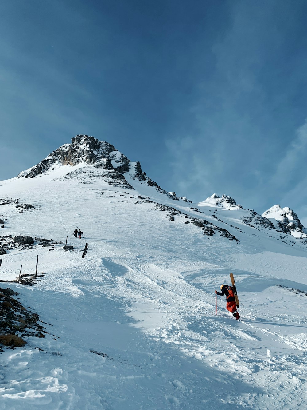 person in orange jacket and black pants standing on snow covered mountain during daytime