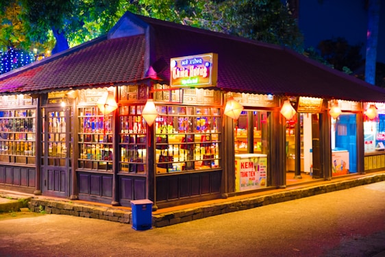 A colorful Vietnamese street food stall bustling with customers enjoying fresh dishes and boba drinks under vibrant lanterns.