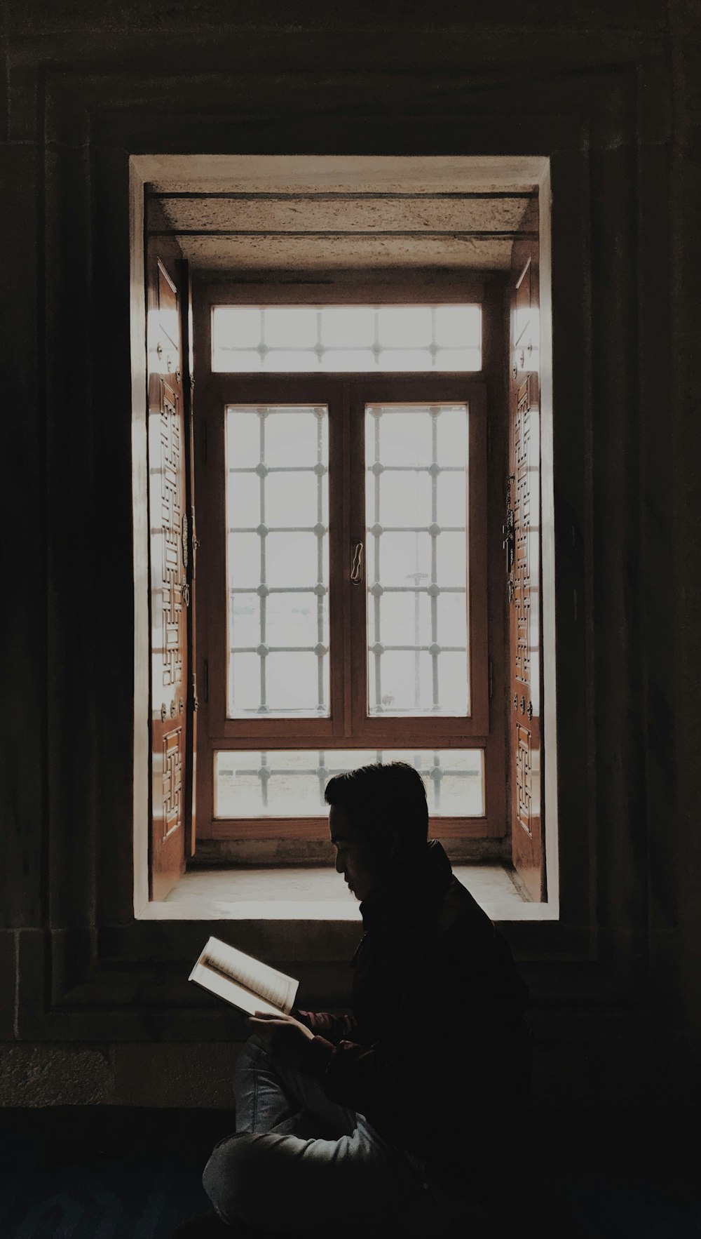 silhouette of man sitting on chair looking at the window