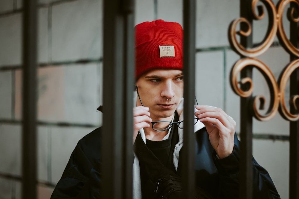 man in black leather jacket wearing red cap