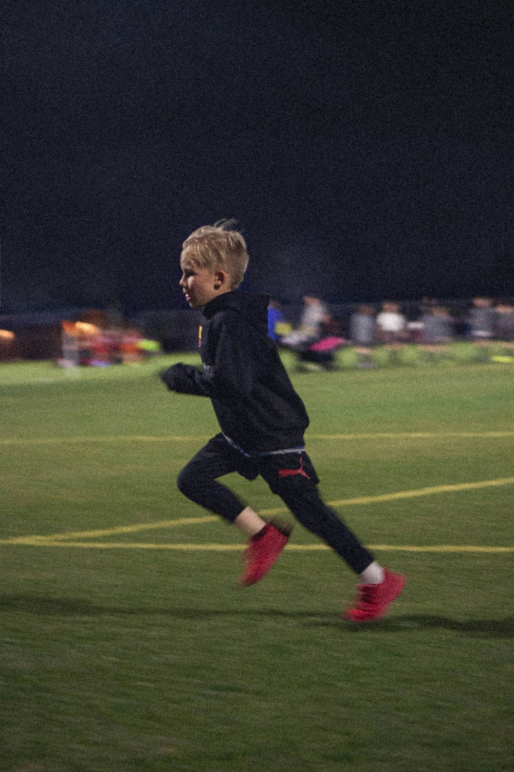 boy in blue long sleeve shirt and black pants running on green grass field during daytime
