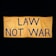 A large yellow fabric banner with bold black letters displaying the message 'LAW NOT WAR' against a dark background.