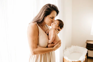 A warm portrait of a midwife gently holding a newborn in a softly lit room