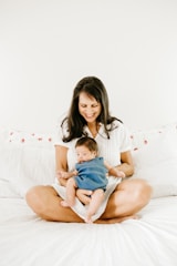 woman in white t-shirt carrying baby in blue onesie