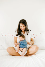 woman in white t-shirt carrying baby in blue onesie
