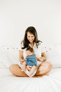 woman in white t-shirt carrying baby in blue onesie