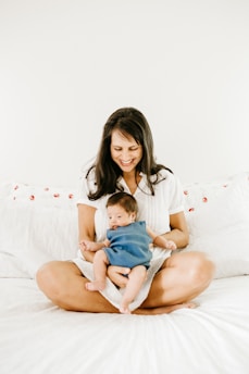woman in white t-shirt carrying baby in blue onesie