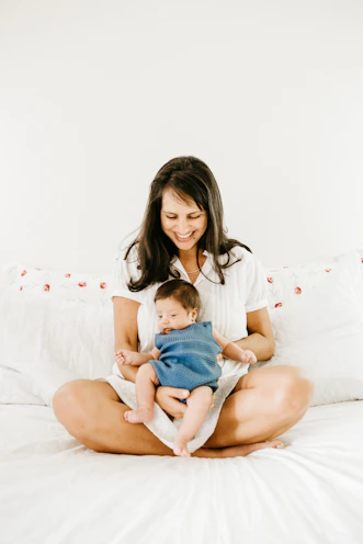 woman in white t-shirt carrying baby in blue onesie