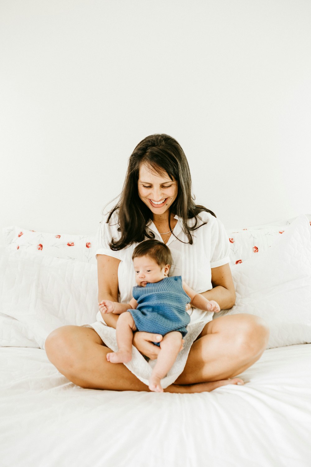 Frau im weißen T-Shirt trägt Baby in blauem Onesie