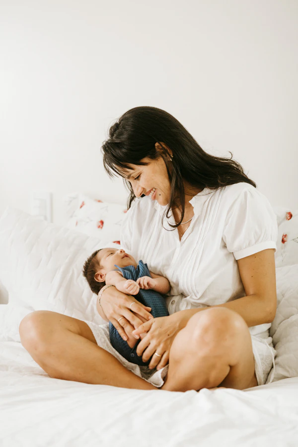 Mother in white shirt tenderly holding newborn baby