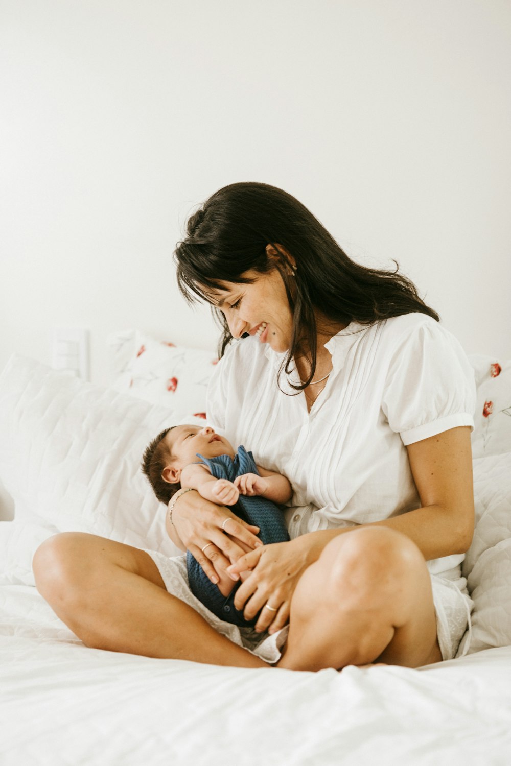 Mujer con camiseta blanca de cuello redondo sosteniendo al bebé