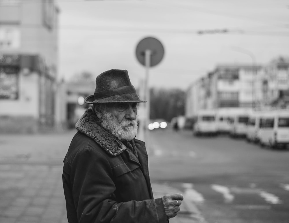 Foto en escala de grises de un hombre con chaqueta negra y sombrero