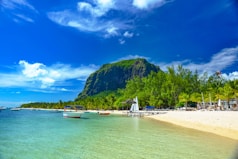 boats on sea shore near green mountain under blue sky during daytime