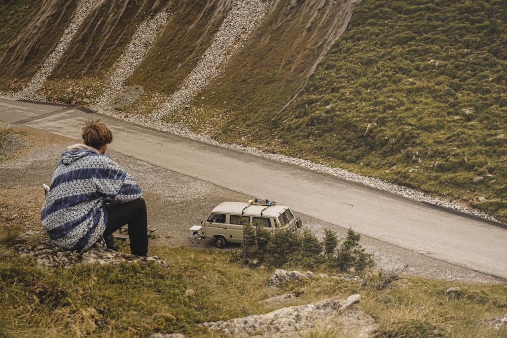 man in blue and white plaid dress shirt sitting on white suv on road during daytime