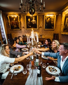 group of people sitting on chair in front of table with plates and drinking glasses