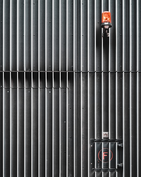 black and red fire extinguisher on gray metal wall