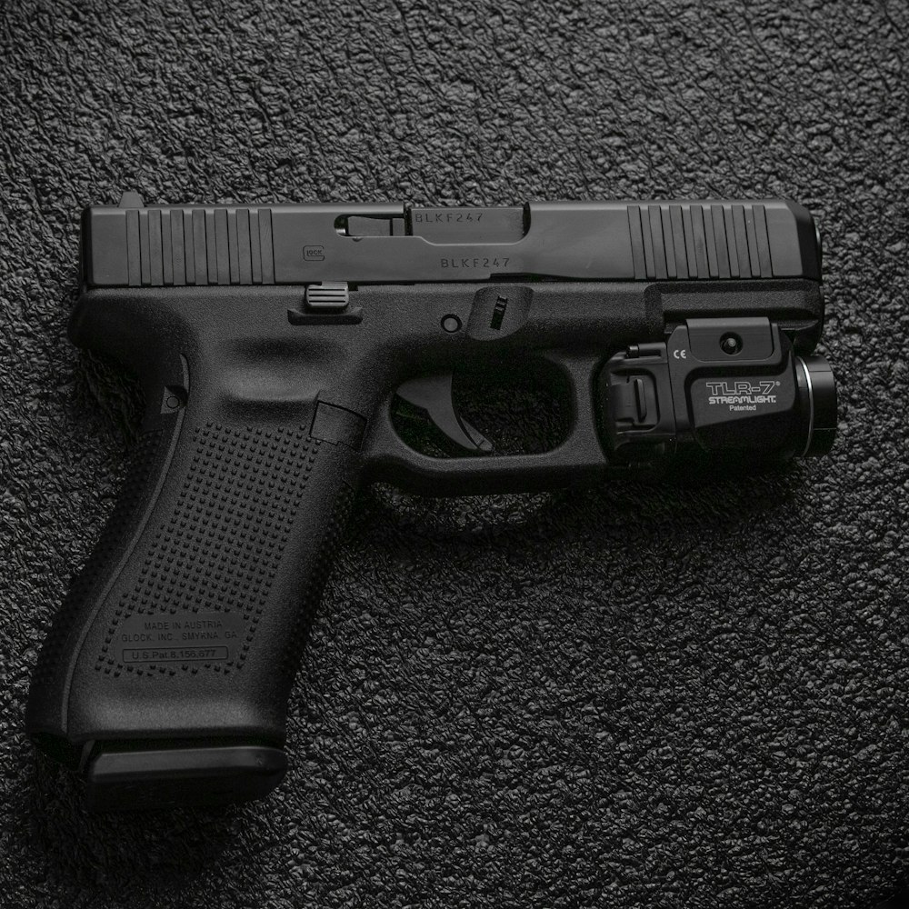 black semi automatic pistol on gray textile