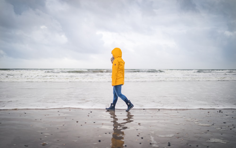 person in yellow hoodie standing on beach during daytime