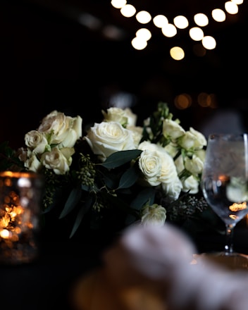 A romantic setting with a couple holding hands, surrounded by soft lighting and floral decorations.