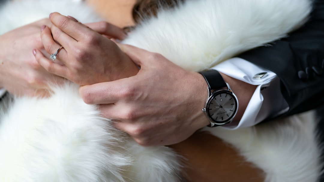 person wearing black and silver watch holding white fur animal