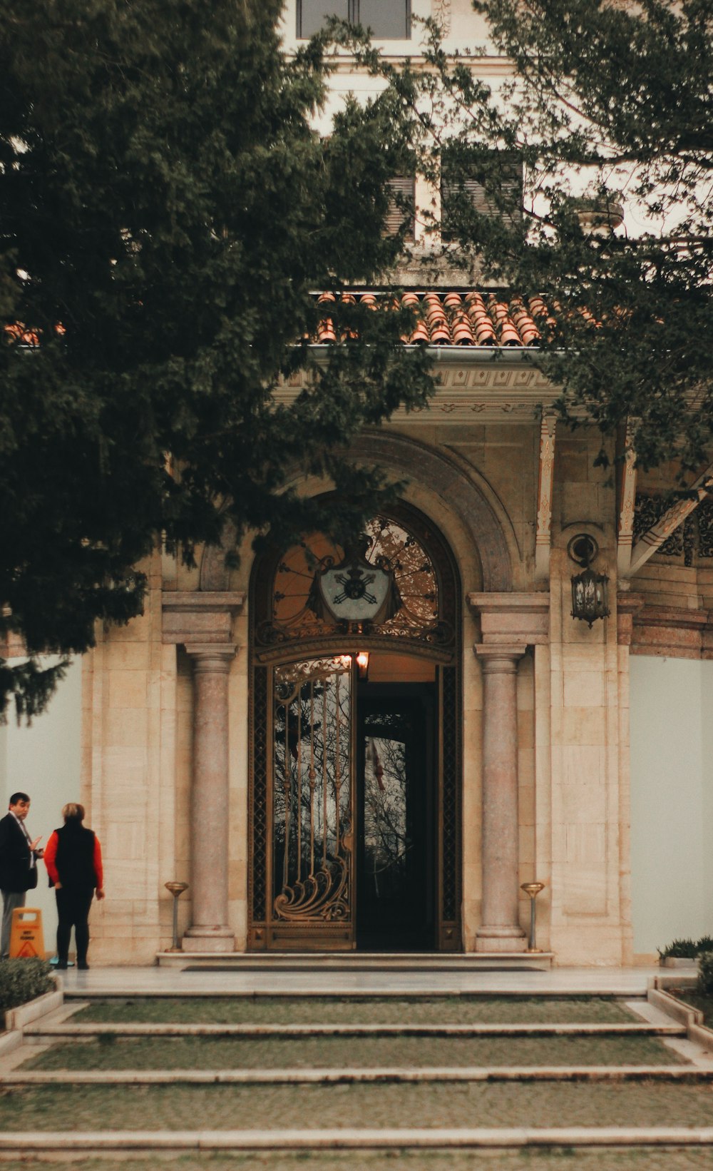 man in black suit standing near black metal gate