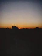 A vibrant sunset behind a silhouette of a person reciting poetry outdoors.